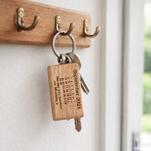 Load image into Gallery viewer, Wooden key ring with keys attached on a white wall.