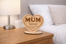 Load image into Gallery viewer, Wooden heart-shaped plaque with 'MUM' and engraved text on a nightstand.